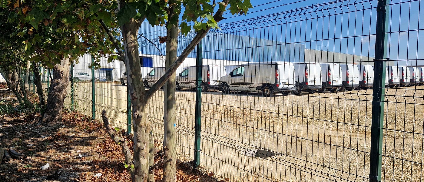 The car park's metal fence, with trees along the boundary